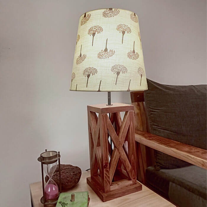 पीले-मुद्रित फैब्रिक लैंपशेड के साथ सममित भूरा लकड़ी का टेबल लैंप